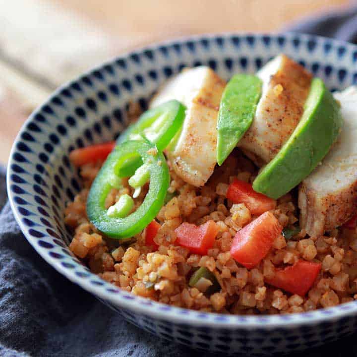 bowl of arroz con pollo garnished with peppers and chicken