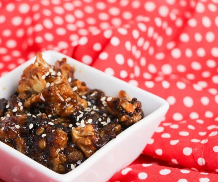 bowl of sticky sesame asian cauliflower on red napkin with white dots