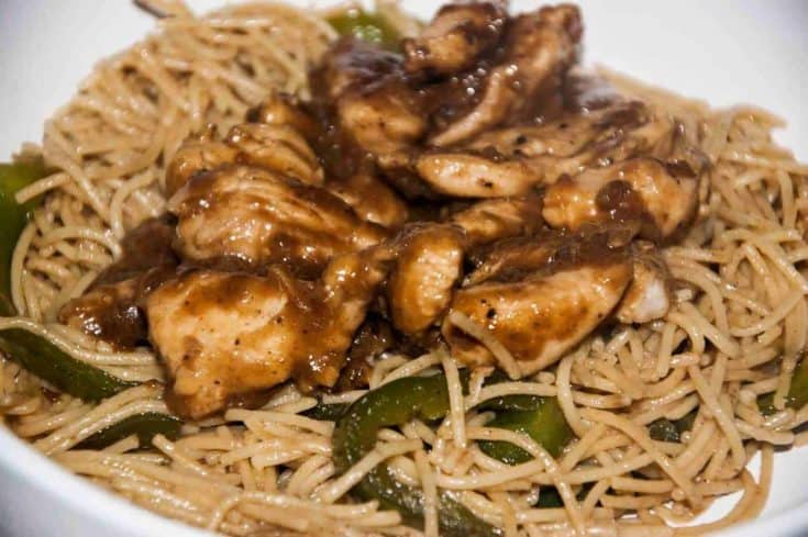 Mongolian Chinese chicken tossed with peppers and noodles on a white plate