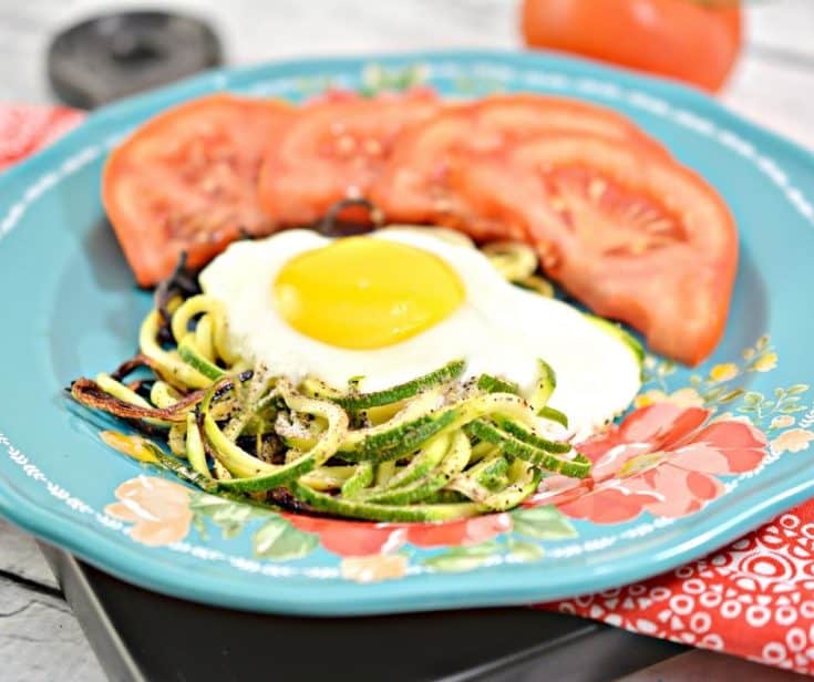 Keto Eggs in a next on top of zoodles with tomato wedges on a plate