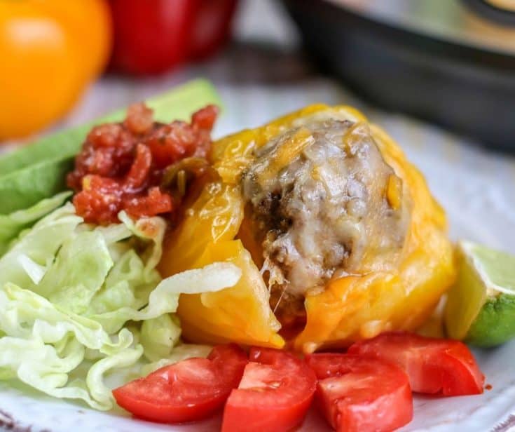 yellow bell pepper stuffed with Mexican flavored beef on a plate with the Instant Pot in the background and a salad